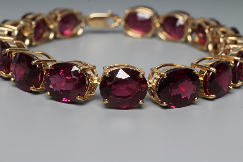 A GARNET BRACELET, the sixteen oval facet cut stones claw set to a plain frame with lobster clasp Image
