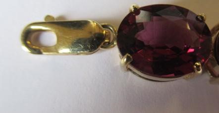 A GARNET BRACELET, the sixteen oval facet cut stones claw set to a plain frame with lobster clasp Image