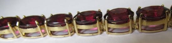 A GARNET BRACELET, the sixteen oval facet cut stones claw set to a plain frame with lobster clasp Image