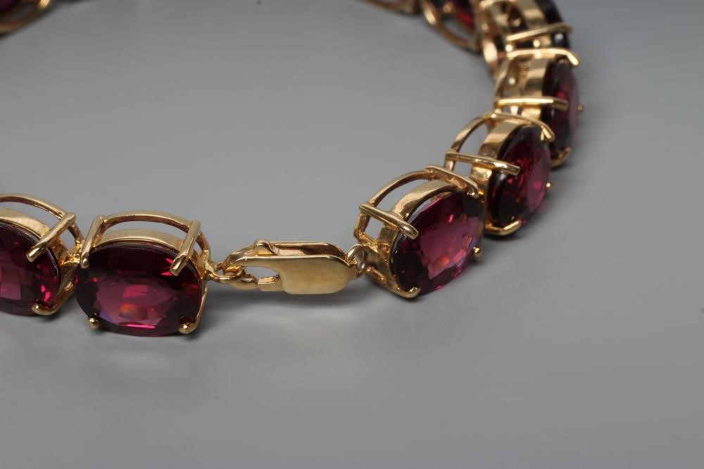 A GARNET BRACELET, the sixteen oval facet cut stones claw set to a plain frame with lobster clasp Image