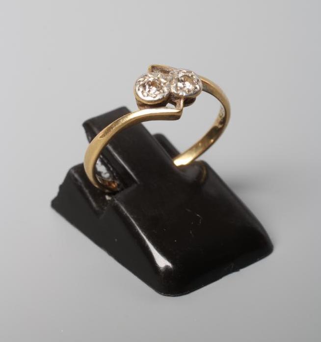 AN ART DECO TWO STONE DIAMOND CROSSOVER RING, the illusion set stones set to angular shoulders and a Image