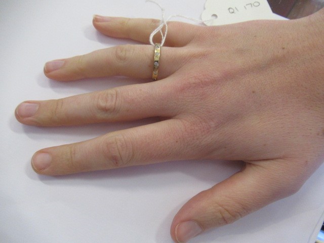 A DIAMOND SET WEDDING RING, the plain 9ct gold band gypsy set with six brilliant cut stones, Image