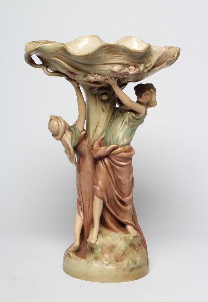 A ROYAL DUX PORCELAIN ART NOUVEAU FIGURAL CENTREPIECE modelled as two young maidens holding aloft a Image