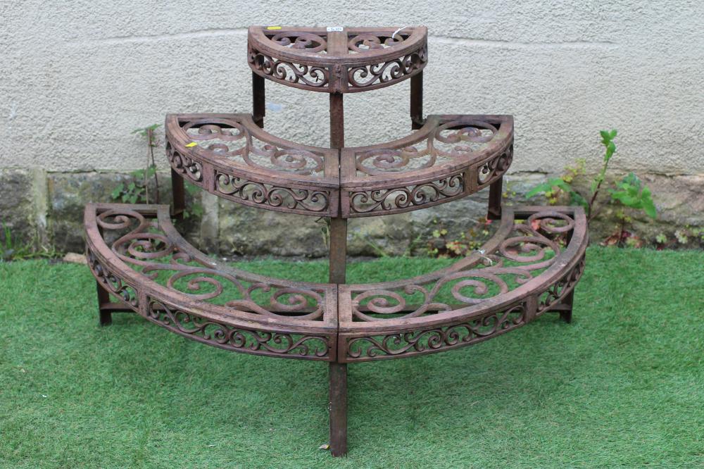 A CAST IRON THREE TIER PLANT ETAGERE of demi lune form pierced with scroll work, on square supports, Image