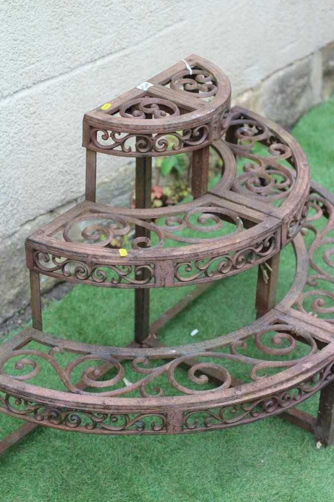 A CAST IRON THREE TIER PLANT ETAGERE of demi lune form pierced with scroll work, on square supports, Image