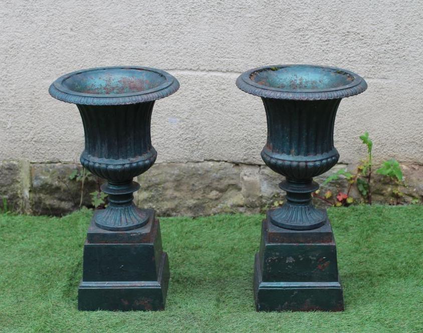 A PAIR OF VICTORIAN CAST IRON URNS of fluted campana form with ovolo rim, turned socle and square Image