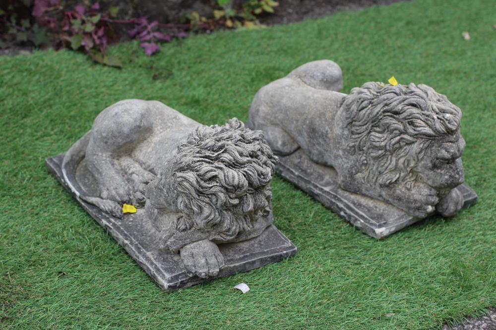A PAIR OF CAST STONE RECUMBENT LIONS on oblong base, 15 1/4" wide (Est. plus 24% premium inc. VAT) Image