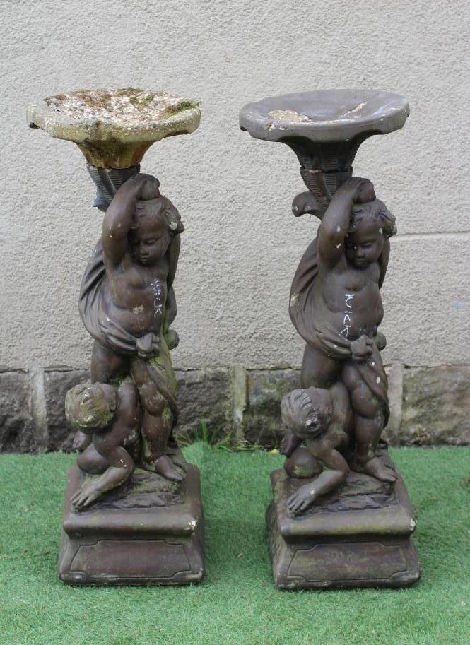 A PAIR OF CAST STONE FIGURAL BIRD BATHS each with two cavorting cherubs supporting a shallow bowl, Image