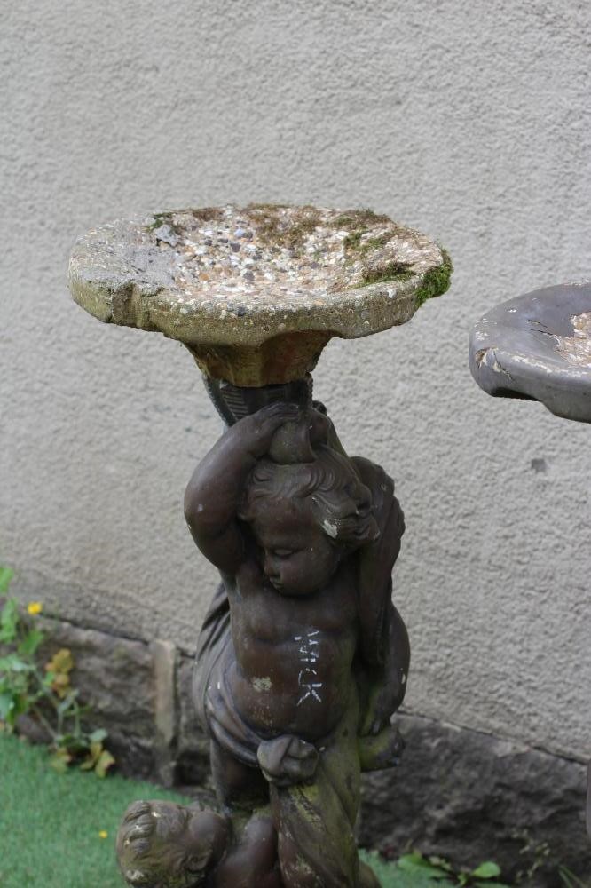 A PAIR OF CAST STONE FIGURAL BIRD BATHS each with two cavorting cherubs supporting a shallow bowl, Image