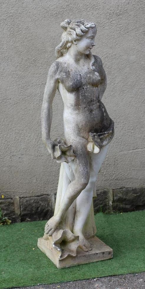 A CAST STONE FIGURE OF A WATER NYMPH, the nude figure standing and holding a shell, another shell at Image
