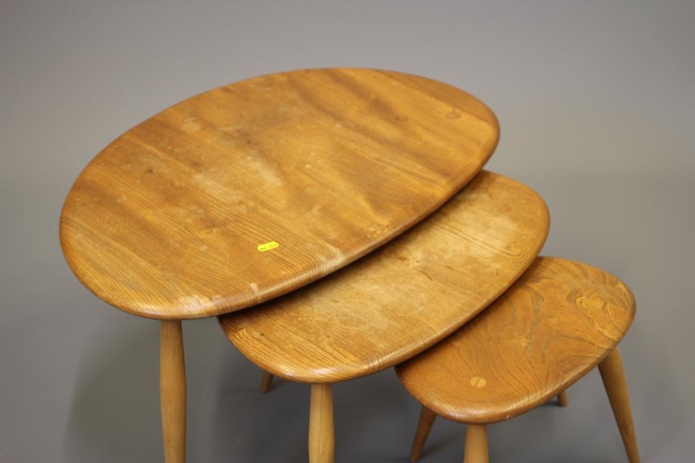 AN ERCOL NEST OF THREE PEBBLE TABLES, Model No.354, with elm top and beech legs, largest 19 3/4" Image
