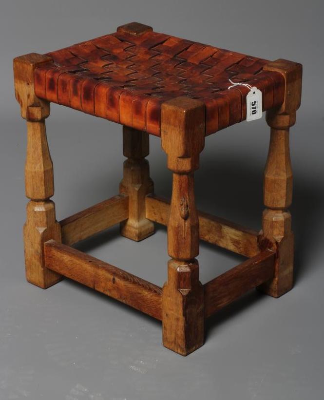 A ROBERT THOMPSON ADZED OAK STOOL of oblong form with strapwork cow hide seat Image