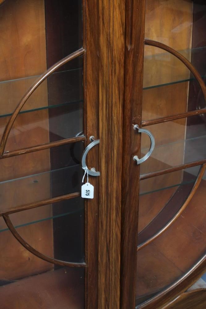 AN ART DECO WALNUT DISPLAY CABINET of circular outline with two astragal glazed doors enclosing Image