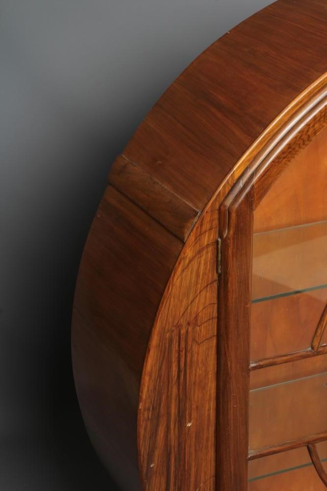 AN ART DECO WALNUT DISPLAY CABINET of circular outline with two astragal glazed doors enclosing Image