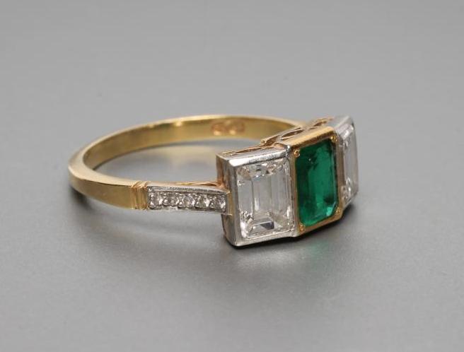 AN EMERALD AND DIAMOND THREE STONE RING Image