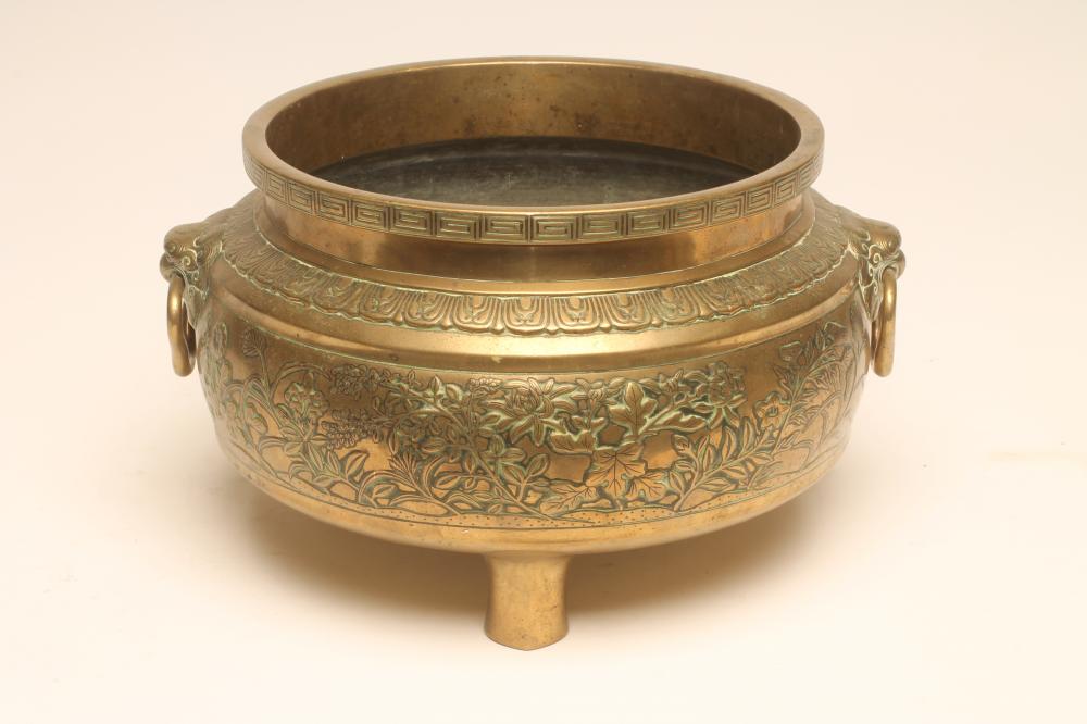 A CHINESE BRONZE CENSOR of cylindrical form with two mask ring handles raised upon three peg feet Image
