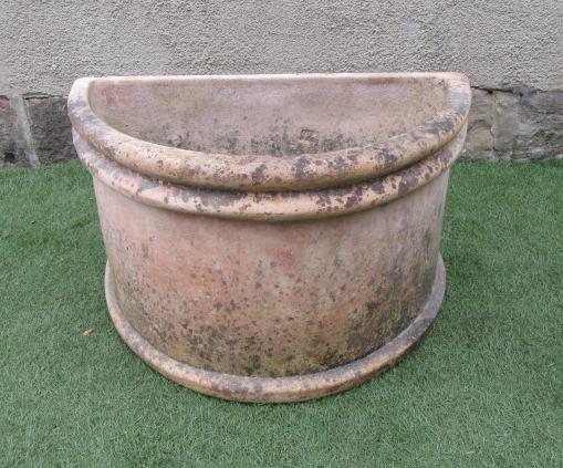 A TERRACOTTA PLANTER of demi lune form with moulded rim and base Image