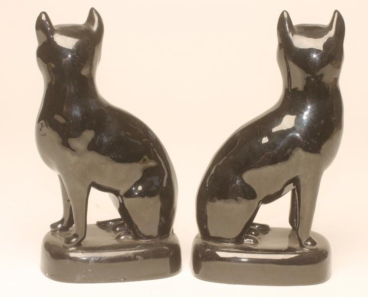 A PAIR OF VICTORIAN BLACK GLAZED STAFFORDSHIRE POTTERY CATS Image