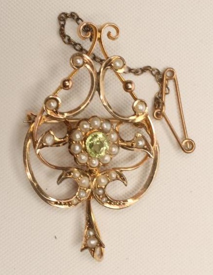 AN EDWARDIAN PERIDOT AND SEED PEARL BROOCH/PENDANT of open scrolling heart form Image