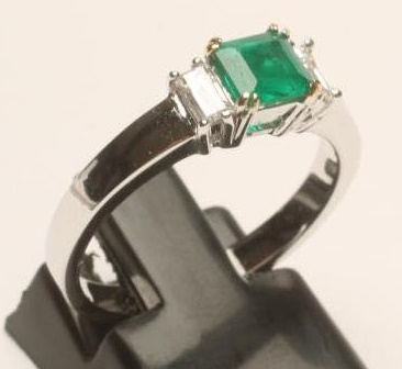 AN EMERALD AND DIAMOND THREE STONE RING Image