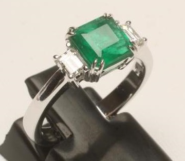 AN EMERALD AND DIAMOND THREE STONE RING Image