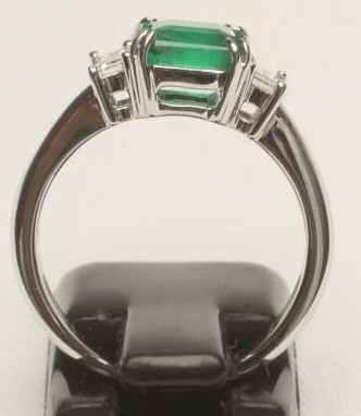 AN EMERALD AND DIAMOND THREE STONE RING Image