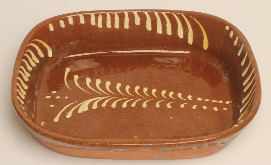A LARGE SLIPWARE BAKING DISH of plain rounded oblong form with cream slip feathered border Image
