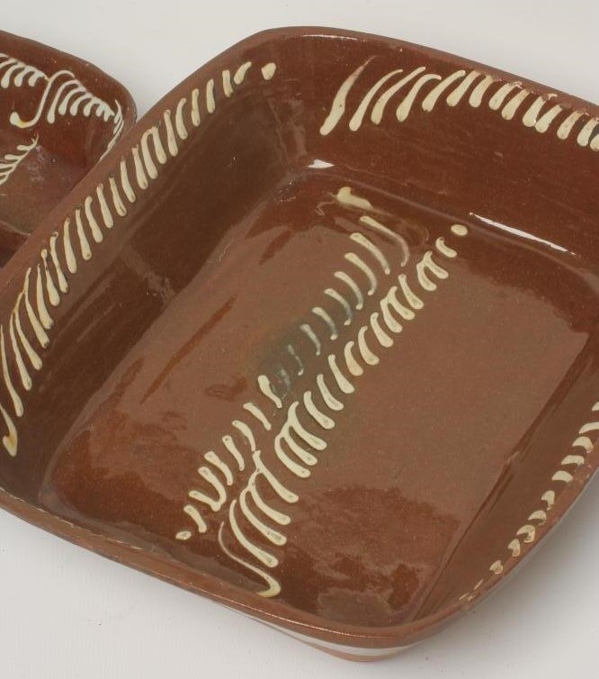 A SLIPWARE BAKING DISH of plain rounded oblong form with pale cream slip feathered border Image