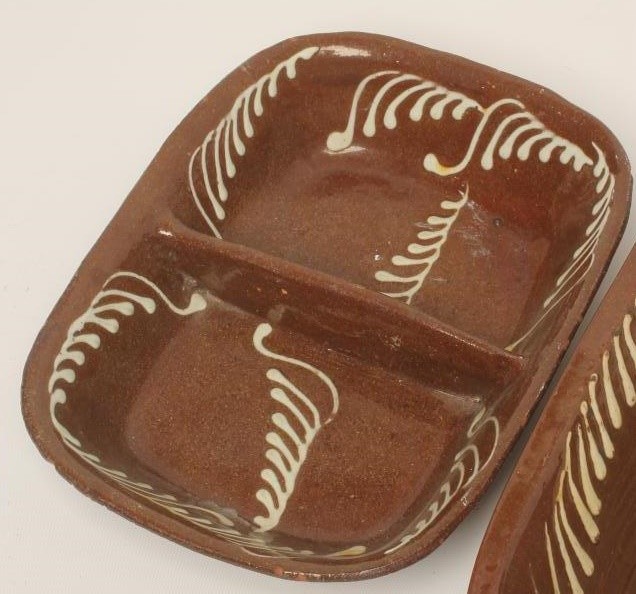 A SLIPWARE BAKING DISH of plain rounded oblong form with pale cream slip feathered border Image