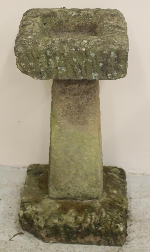 A SANDSTONE BIRD BATH of rough hewn square form with square tapering column and mildly domed base Image