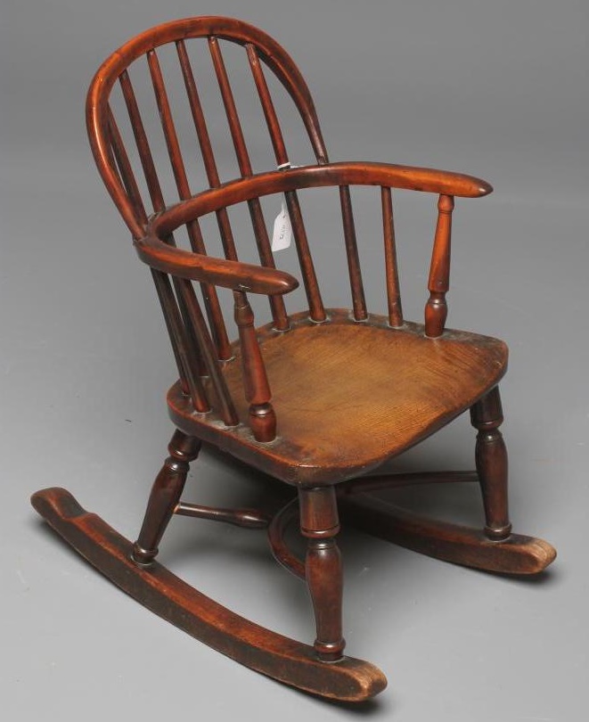 A CHILD'S YEW WOOD WINDSOR ROCKING CHAIR of low hooped stick back form Image