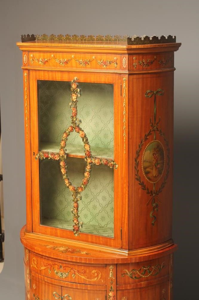 AN EDWARDIAN SATINWOOD TWO STAGE DISPLAY CABINET of demi lune form painted with floral festoons and Image
