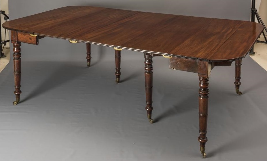 A FINE QUALITY REGENCY MAHOGANY EXTENDING DINING TABLE of rounded oblong form with ebony stringing Image
