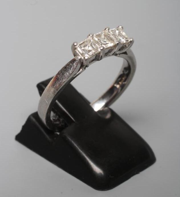 A THREE STONE DIAMOND RING, the Princess cut stones point set to a plain platinum shank, size N Image