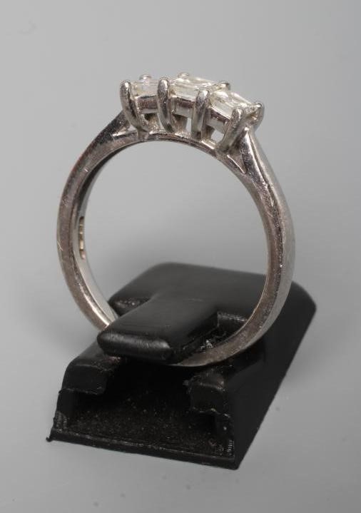A THREE STONE DIAMOND RING, the Princess cut stones point set to a plain platinum shank, size N Image