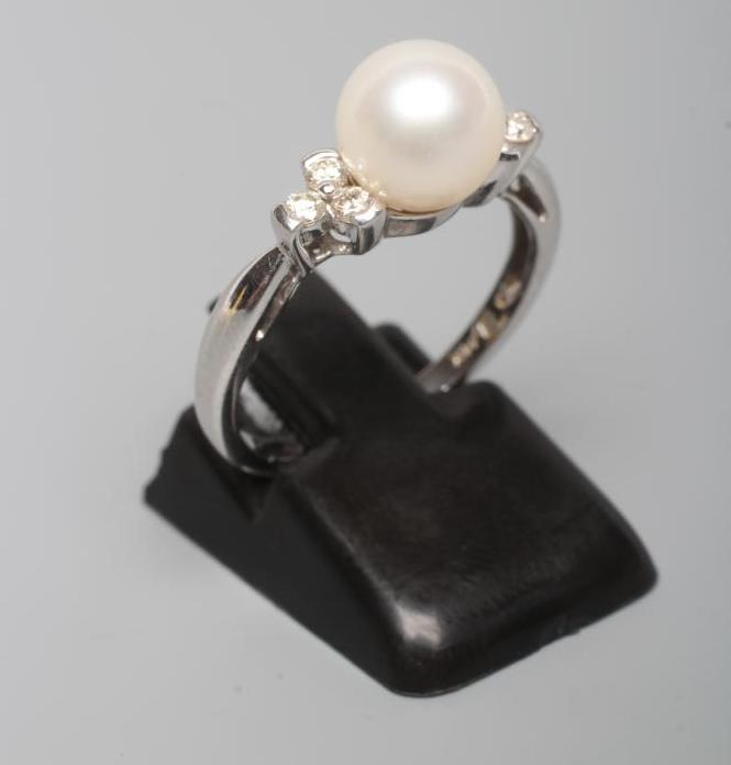 A CULTURED PEARL RING, the white pearl set to shoulders line set with three small diamonds to a Image