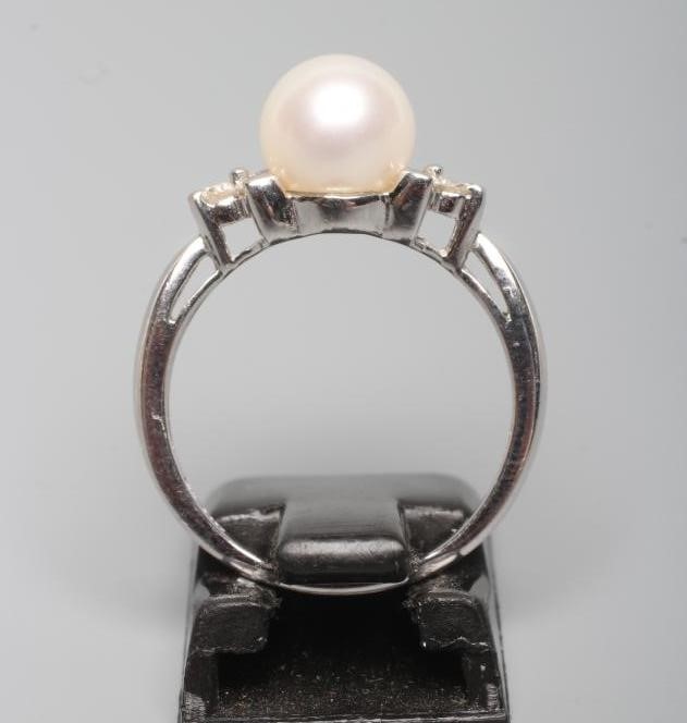 A CULTURED PEARL RING, the white pearl set to shoulders line set with three small diamonds to a Image