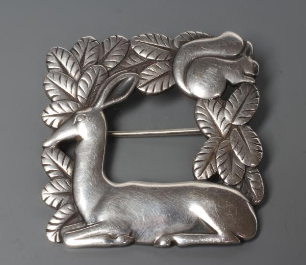 A GEORG JENSEN SILVER SQUARE BROOCH designed by Arno Malinowski, cast as a recumbent deer and Image