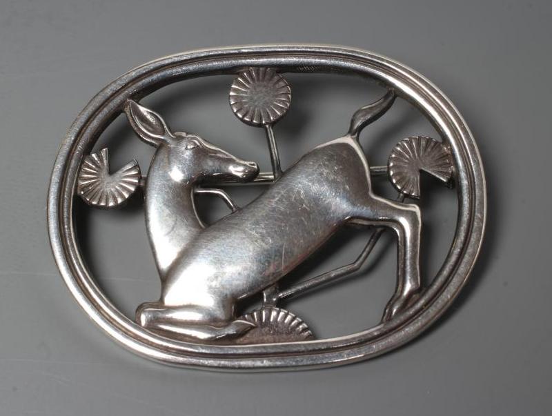 A GEORG JENSEN SILVER OVAL BROOCH designed by Arno Malinowski, cast as a kneeling deer, stamped and Image