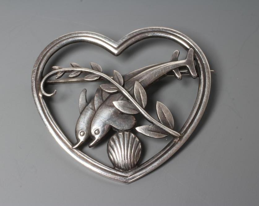 A GEORG JENSEN SILVER HEART BROOCH designed by Arno Malinowski, cast as two dolphins swimming amidst Image