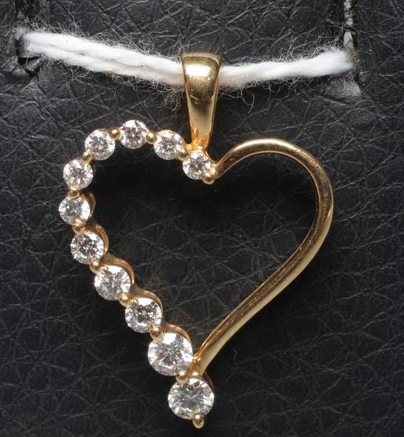 A DIAMOND HEART PENDANT, the slender open heart half set with eleven graduated stones to a fixed Image
