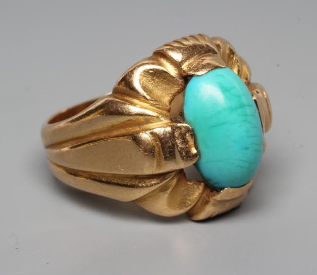 A GENTLEMAN'S RING, the oval cabochon polished turquoise set to an open fancy surround and wide Image