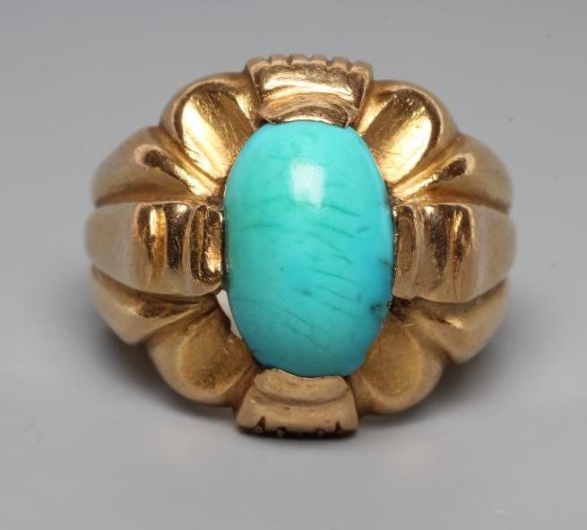A GENTLEMAN'S RING, the oval cabochon polished turquoise set to an open fancy surround and wide Image