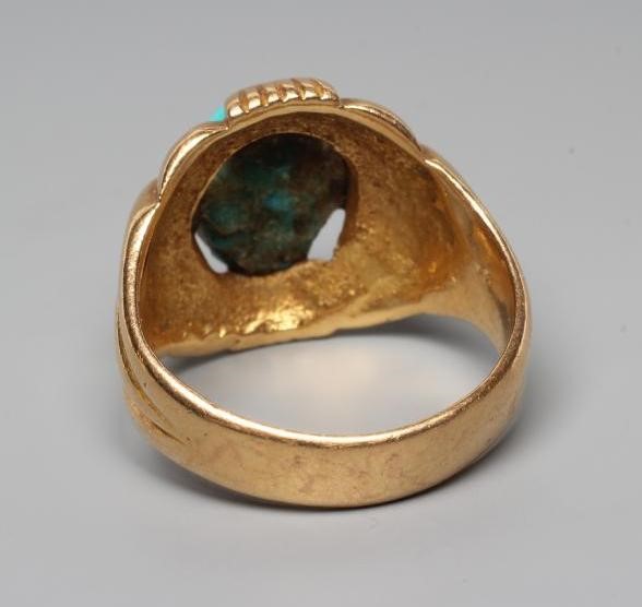 A GENTLEMAN'S RING, the oval cabochon polished turquoise set to an open fancy surround and wide Image