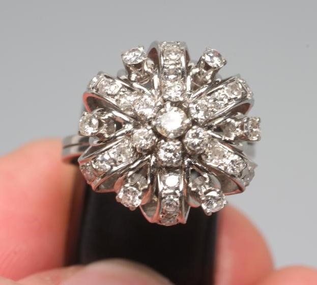A DIAMOND DRESS RING, the seven stone central cluster claw set to an open ribbon tied border with Image