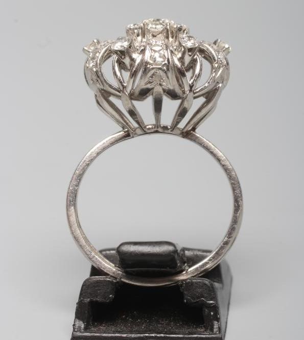 A DIAMOND DRESS RING, the seven stone central cluster claw set to an open ribbon tied border with Image