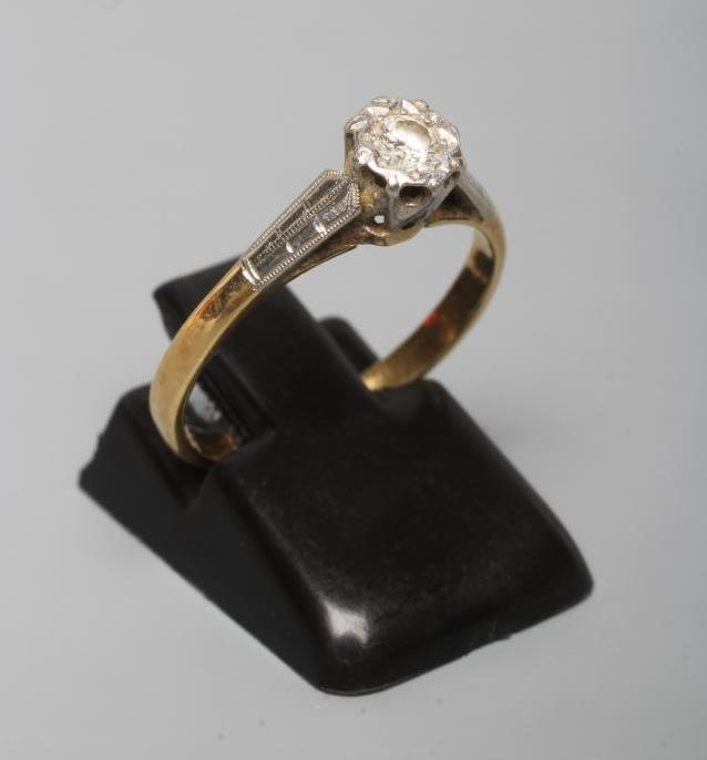 A SOLITAIRE DIAMOND RING, the brilliant cut stone illusion set to geometric engraved white shoulders Image