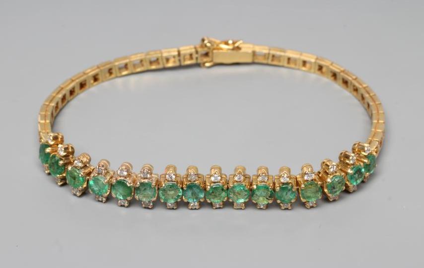 AN EMERALD AND DIAMOND BRACELET, the sixteen circular facet cut emeralds each flanked by two small Image