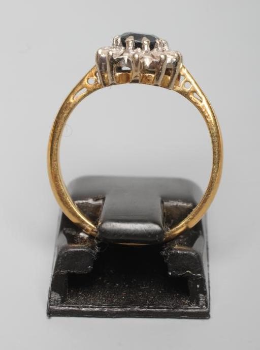 A SAPPHIRE AND DIAMOND CLUSTER RING, the oval facet cut sapphire claw set to a border of ten small Image