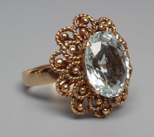 AN AQUAMARINE COCKTAIL RING, the oval facet cut stone claw set to a rope twist open border and plain Image